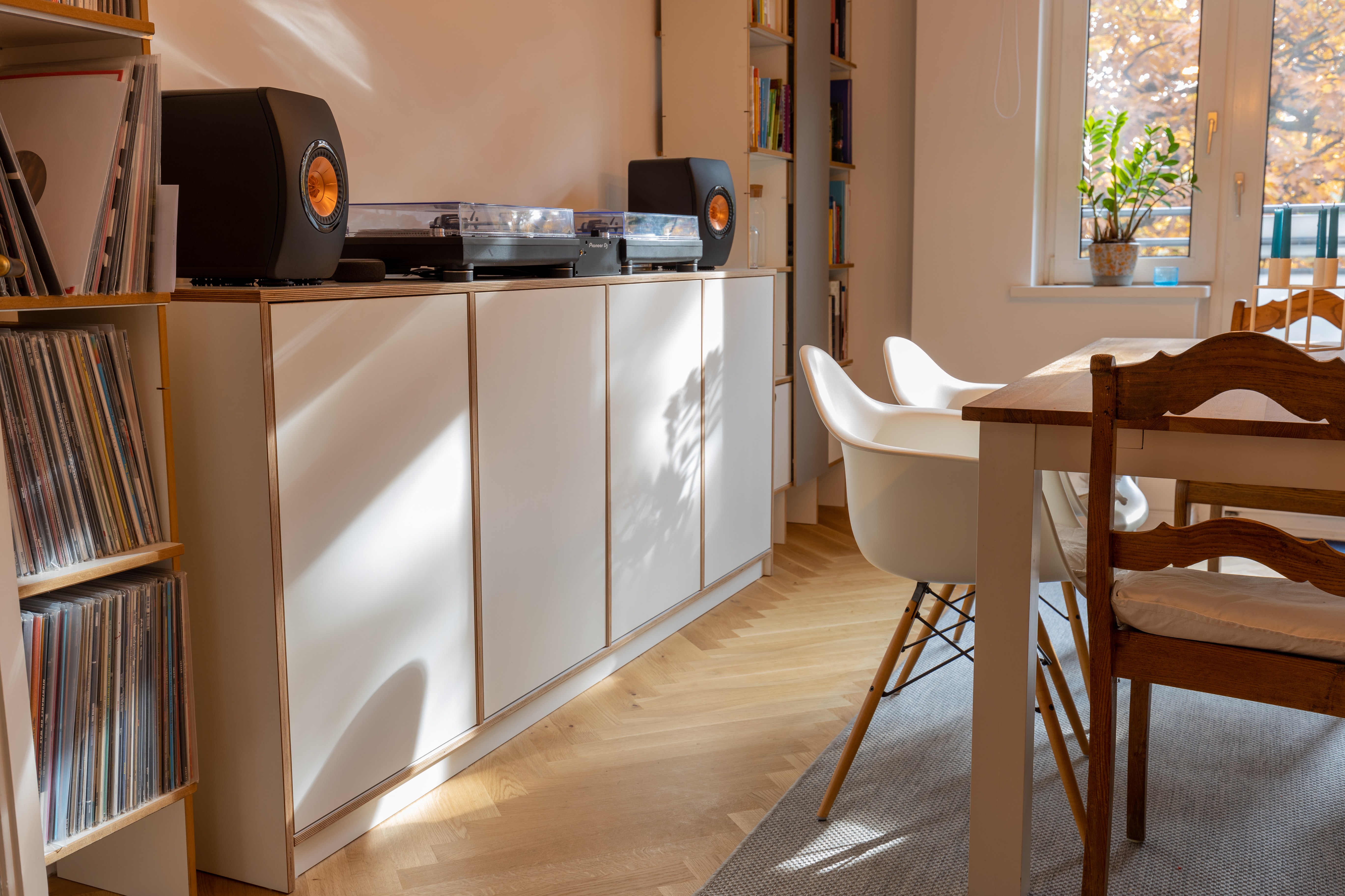 Luxury vinyl flooring, whte and brown cabinets, sunshine coming through dining room, with small bookshelve, and speaker with stereo on counter. 